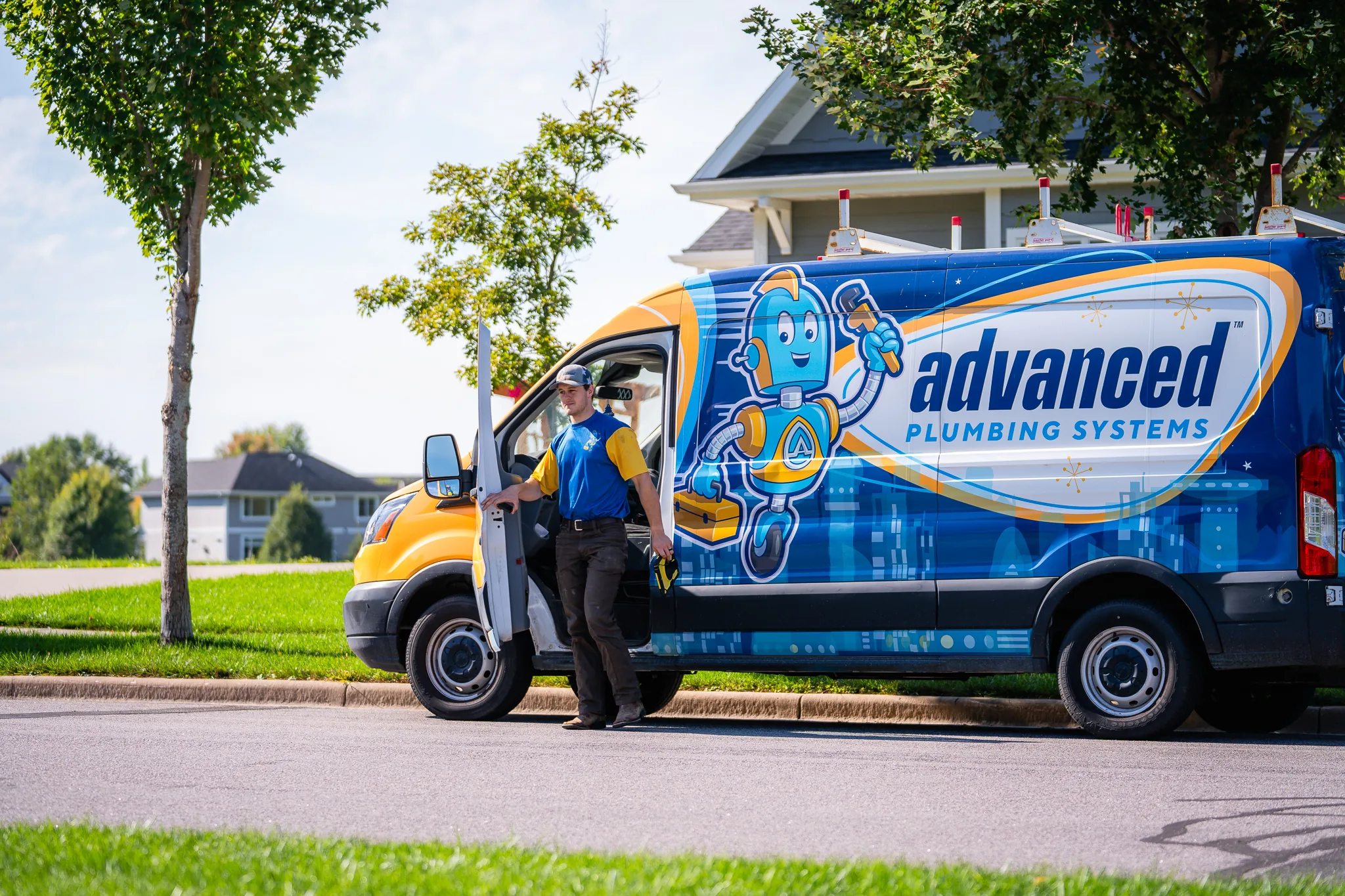 Advanced Plumbing Systems service van with technician standing in residential neighborhood.