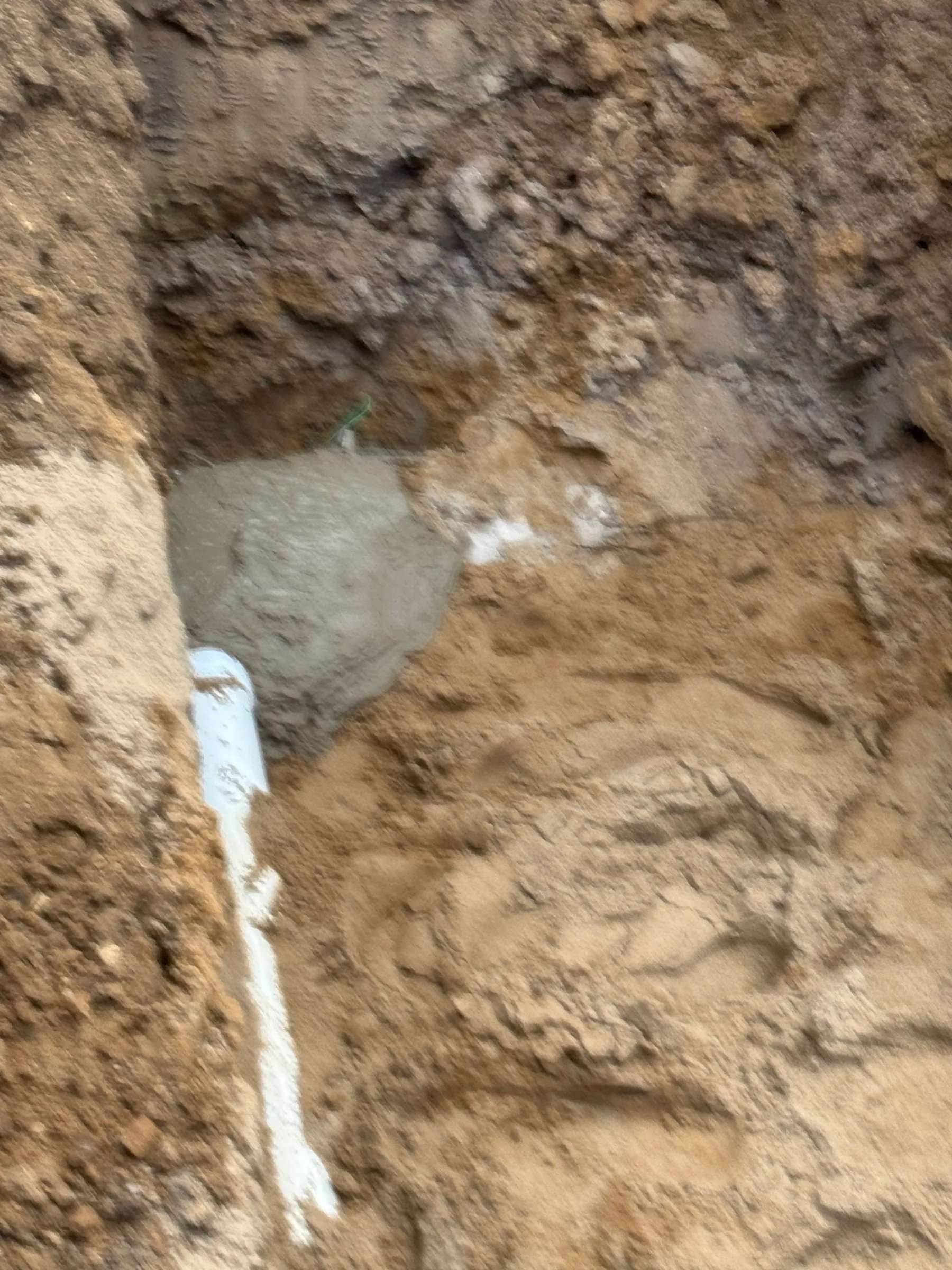 Excavated soil and pipe during plumbing repair work showing underground infrastructure.