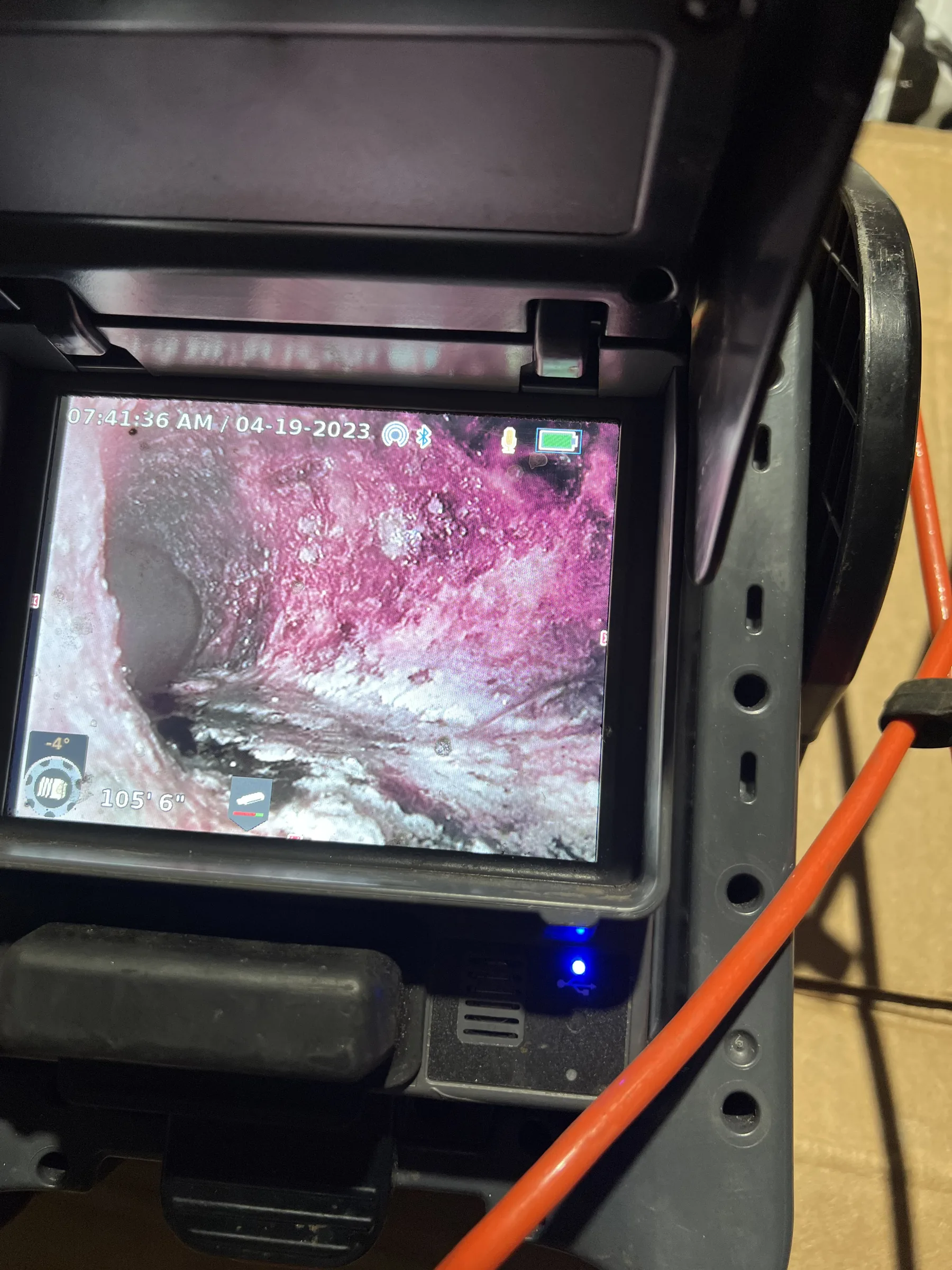Plumbing inspection camera display showing pink and white mineral deposits inside a pipe.