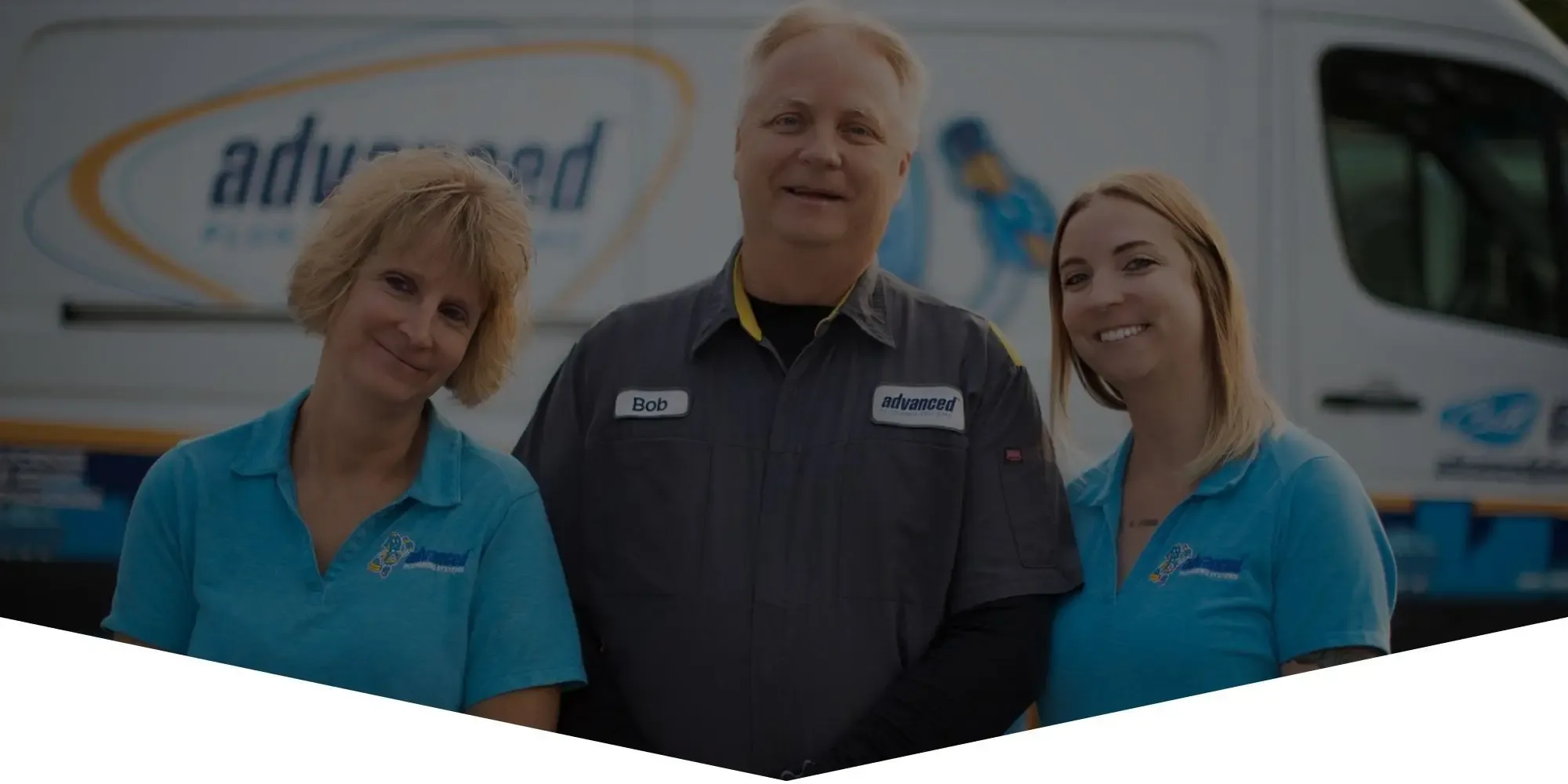 Three plumbing service technicians smiling in front of an Advanced service van.