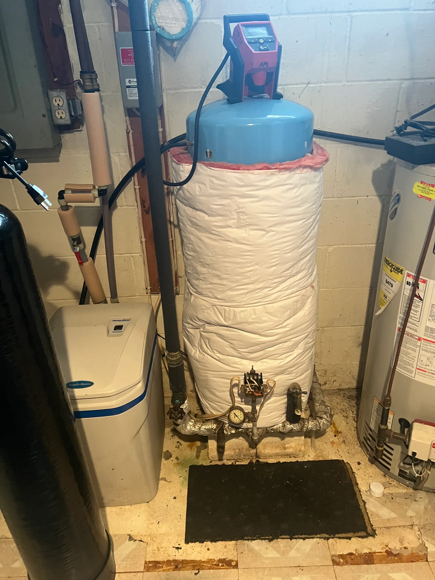 Water heater tank with blue top and white insulation in basement utility room.