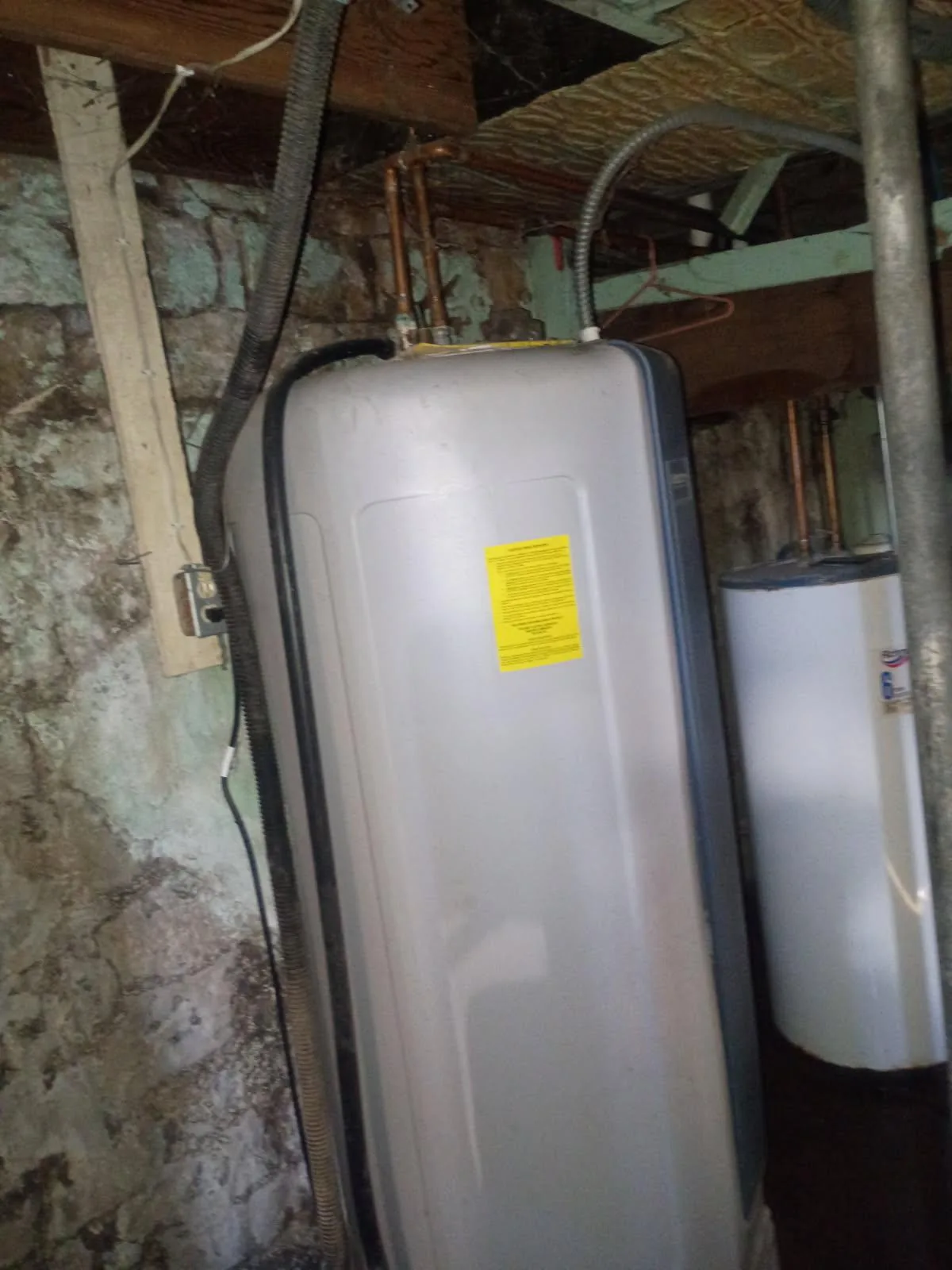 Water softener system with yellow tag installed in basement utility area.